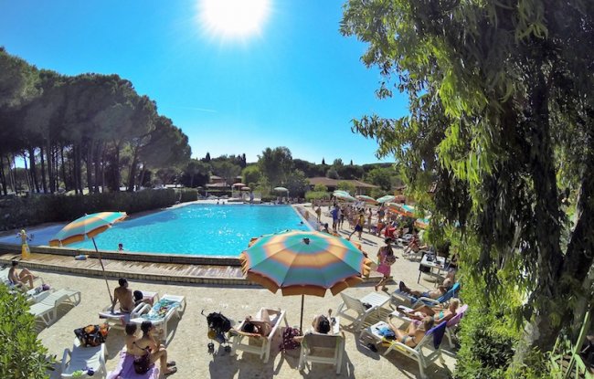 Piscina soleggiata con lettini e ombrelloni colorati.