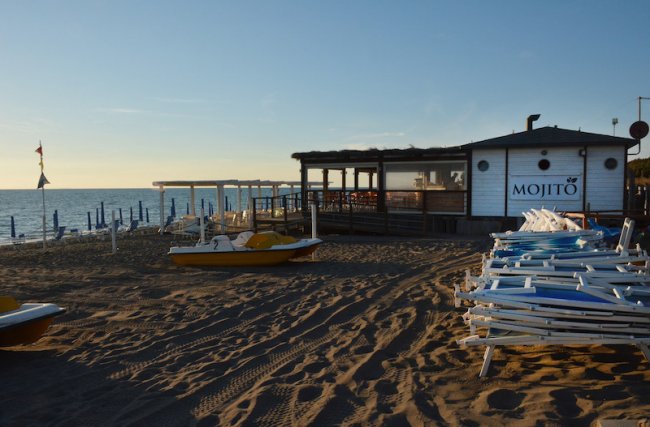 Spiaggia con stabilimento e pedalò al tramonto.