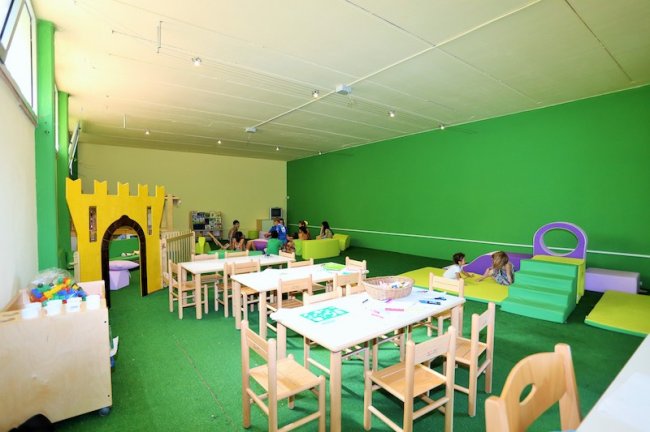 Sala giochi per bambini con tavoli e giochi colorati.