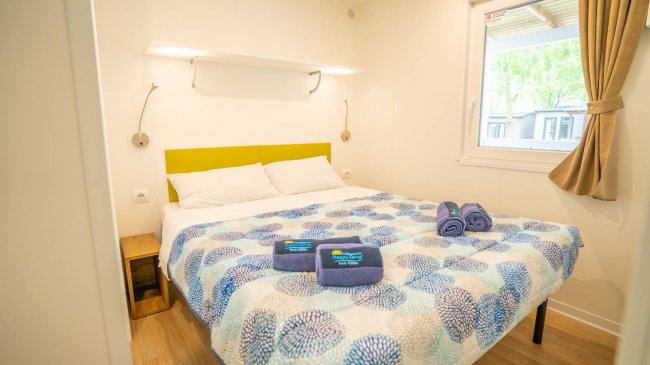 Una camera da letto con letto matrimoniale, coperta colorata e asciugamani piegati.