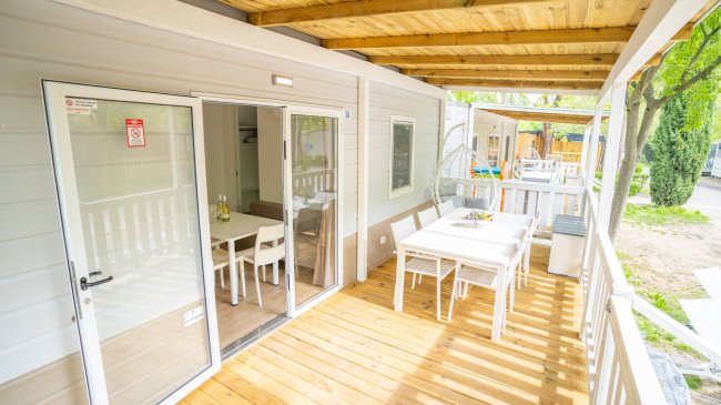 Terrazza con tavolo, sedie e poltrona sospesa.