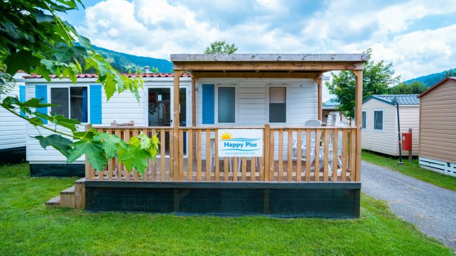 Una casa mobile bianca con veranda in legno su un prato.