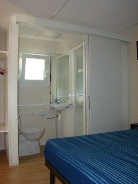 Bagno compatto con WC, lavabo e doccia, letto a sinistra.