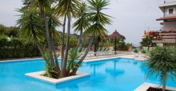 Piscina con palme al centro, circondata da sdraio.