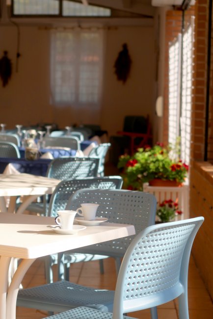 Dettaglio di un tavolo con tazzine e sedie azzurre.