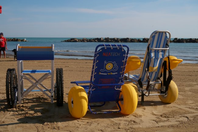 Sedie a rotelle da spiaggia sulla sabbia vicino al mare.