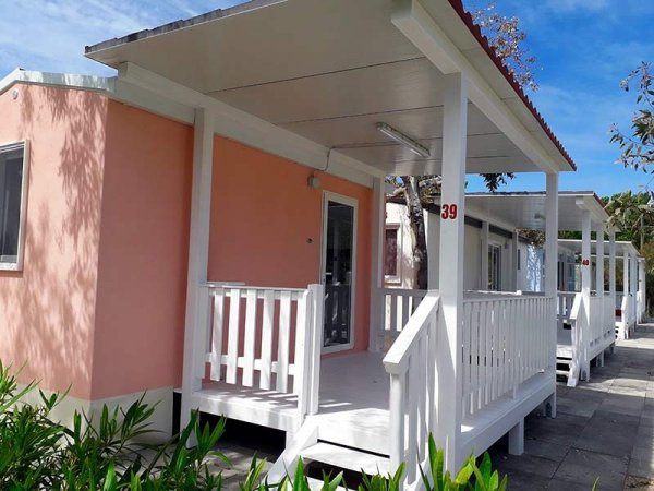 Bungalow rosa con veranda bianca.