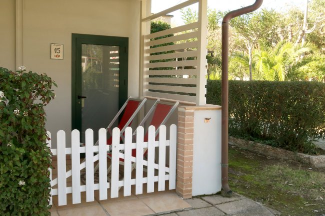 Veranda con due sdraio e recinto bianco.
