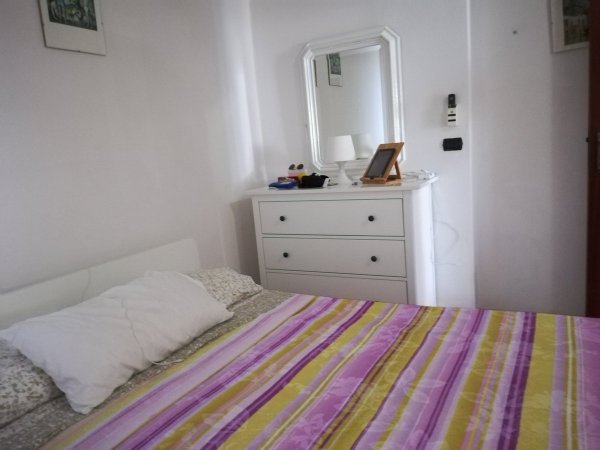 Camera da letto con letto a fantasia e comò bianco.