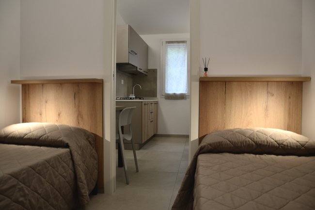 Camera con letti singoli e piccola cucina.