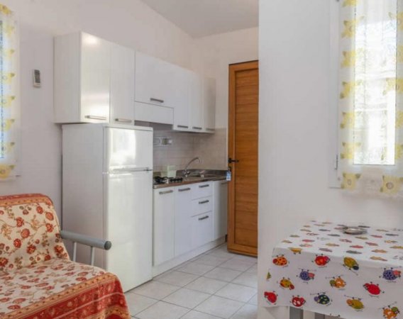 Cucina compatta con frigo e tavolo colorato.