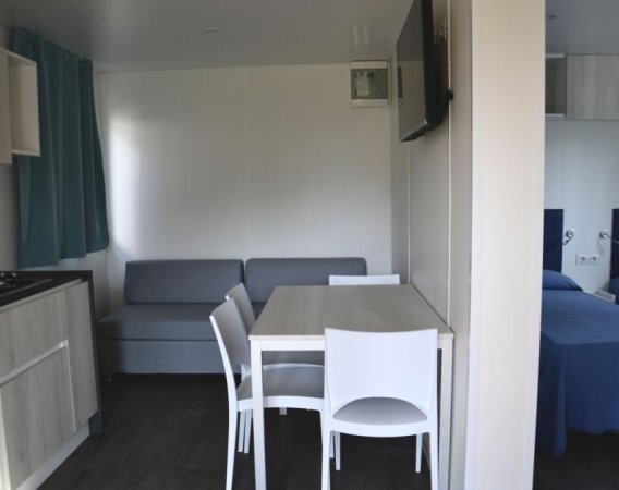 Soggiorno con divano, tavolo e sedie bianche.