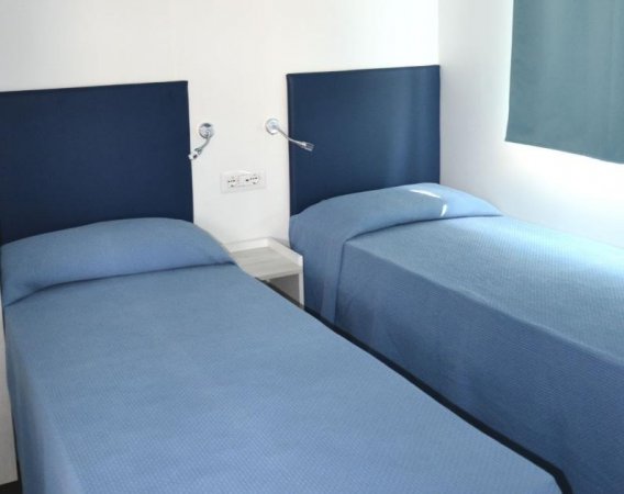 Camera con due letti singoli coperti di blu.