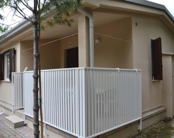 Casa beige con veranda recintata bianca.