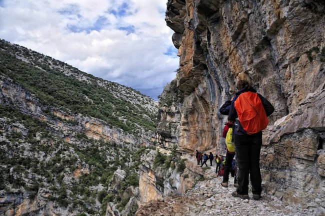 Escursionisti camminano su una stretta pista montana.