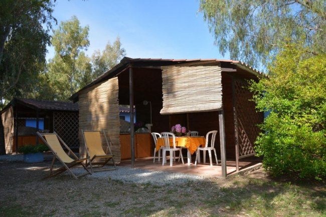 Bungalow rustico con sedie e sdraio all'aperto.