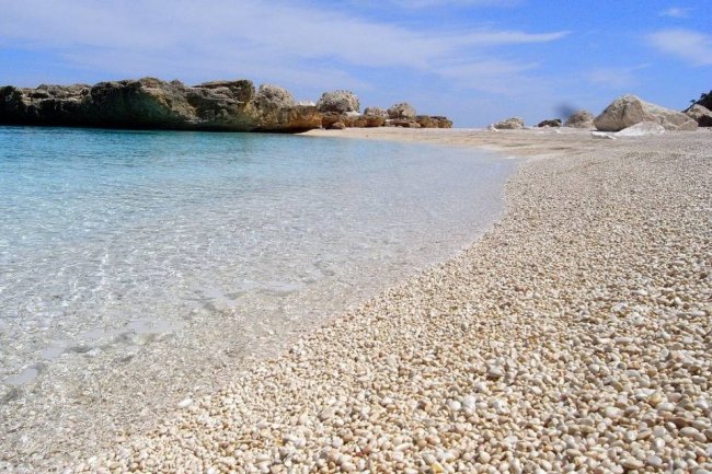 Spiaggia con ciottoli e mare limpido.