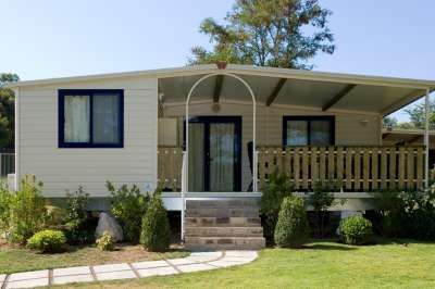 Casa mobile con veranda coperta, circondata da prato e piante.