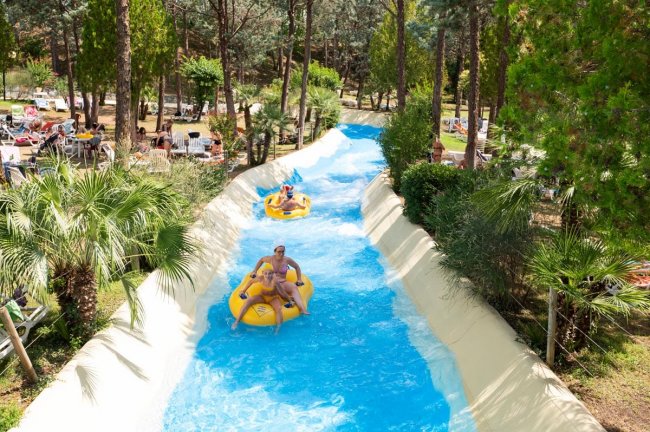 Persone scendono un toboga gommoni in un parco acquatico.