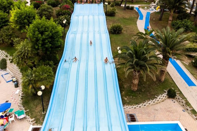 Diverse persone scendono un grande scivolo acquatico.
