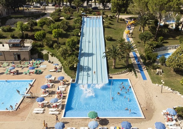 Scivolo acquatico con piscina e bagnanti intorno.