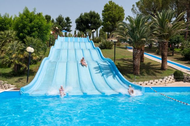 Scivoli d'acqua blu con persone che scivolano in piscina.