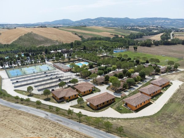 Veduta aerea di un complesso turistico con piscine e campi sportivi.