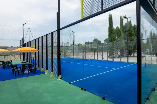 Un campo da padel all'aperto con recinzioni in vetro.