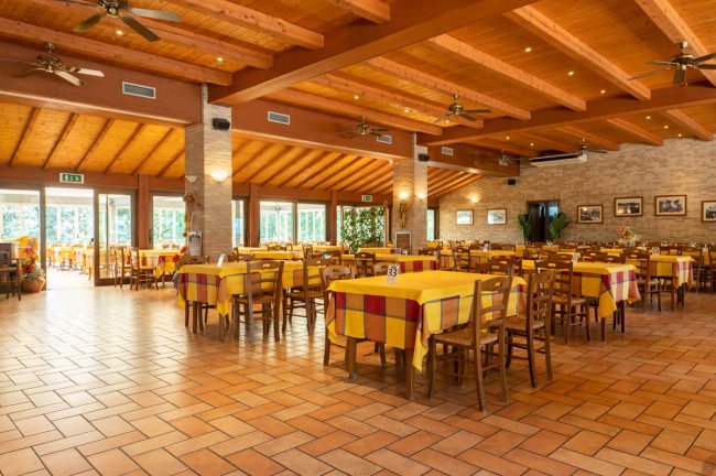 Ristorante spazioso con travi in legno e tavoli gialli.