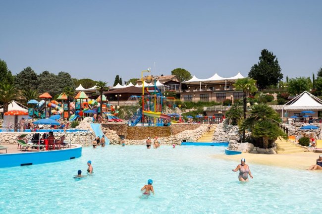Piscina con giochi d'acqua colorati e lettini.