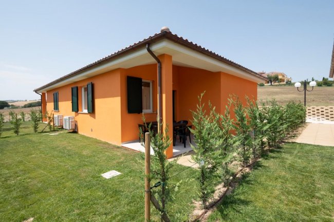 Casa arancione con giardino recintato da siepi.