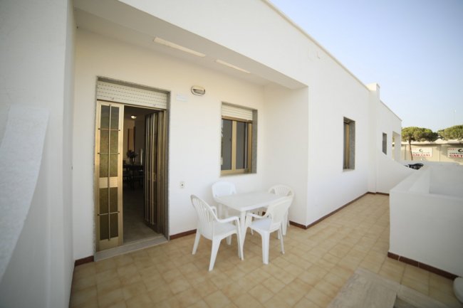 Terrazza con tavolo e sedie bianche.