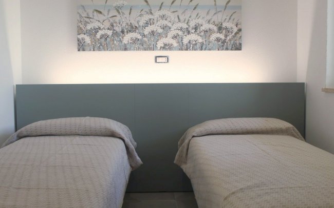 Due letti singoli con copriletti beige e quadro di fiori sopra.