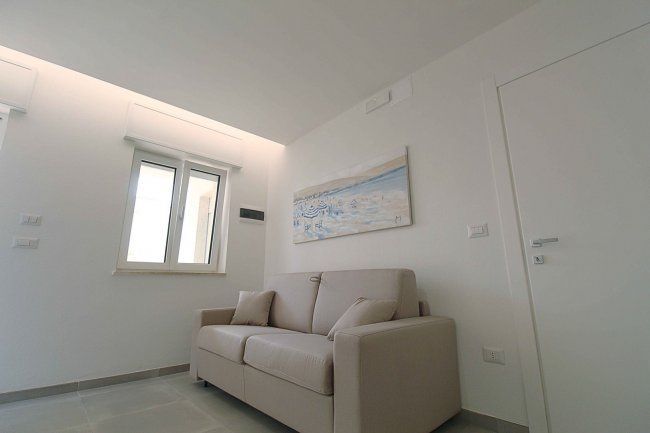 Sala con divano beige e finestra.