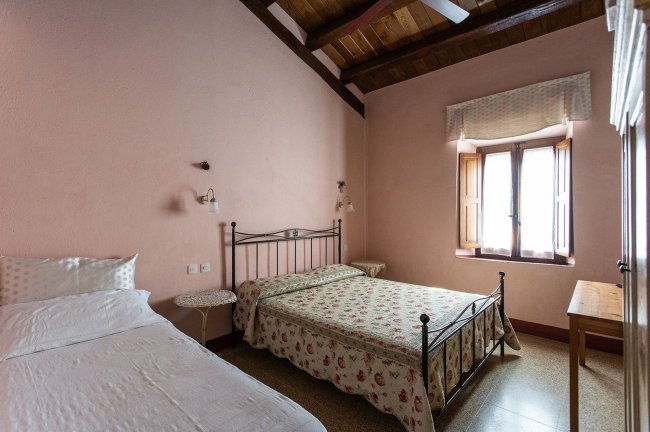 Camera da letto con pareti rosa e due letti.