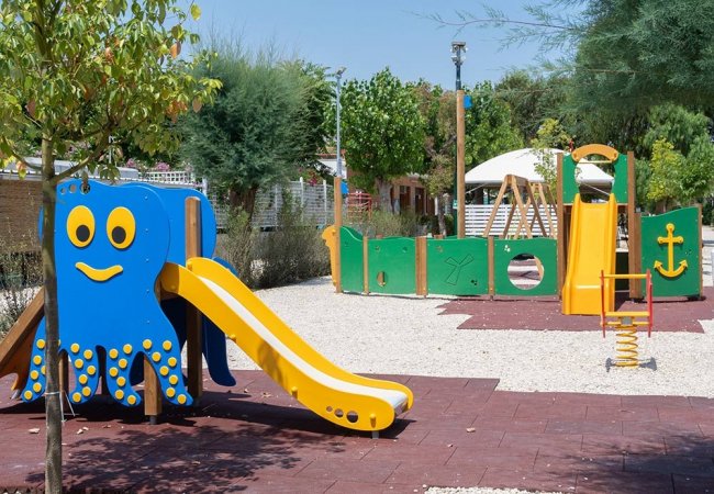 Parco giochi con scivolo a forma di polpo e strutture colorate.