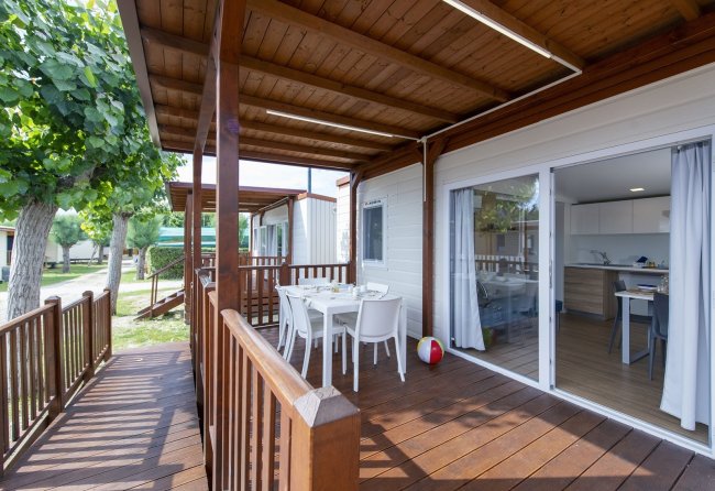 Terrazza con tavolo bianco e sedie sotto pergola di legno.