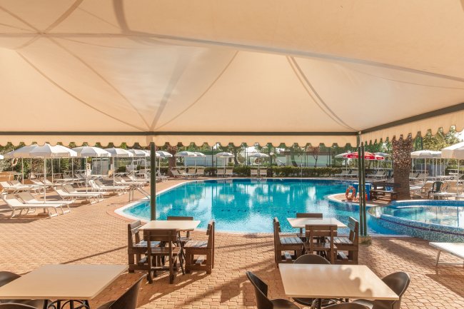 Tavoli sotto un tendone affacciati su una piscina.