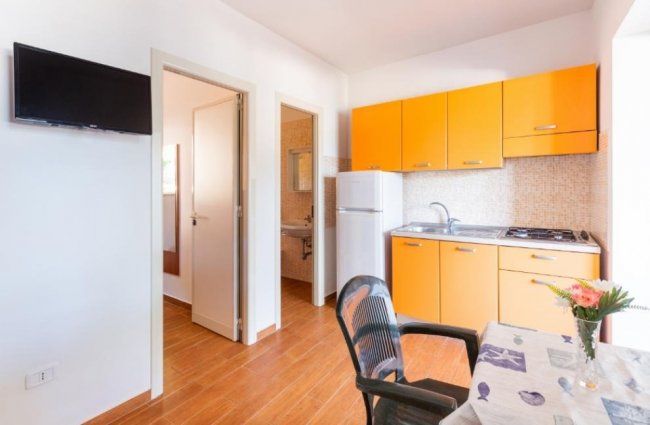 Cucina arancione con tavolo e sedie.