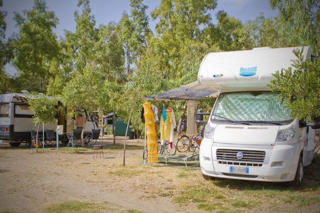 Camper parcheggiati in un'area campeggio con vestiti che asciugano vicino.
