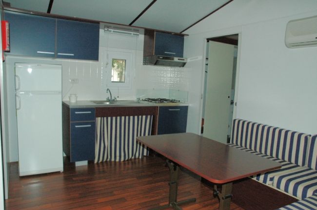 Una cucina con mobili blu, frigorifero bianco e tavolo in legno. Pavimenti in legno scuro.