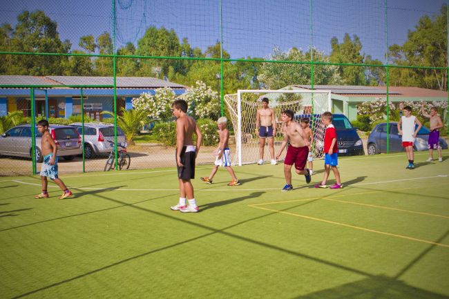 Ragazzi giocano a calcio su un campo all'aperto.