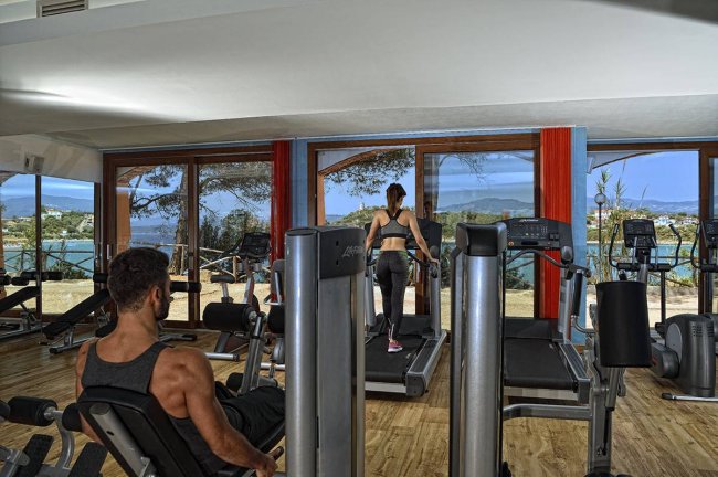 Palestra con vista mare, persone su tapis roulant.