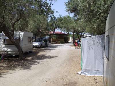 Area campeggio con roulotte, auto e alberi.