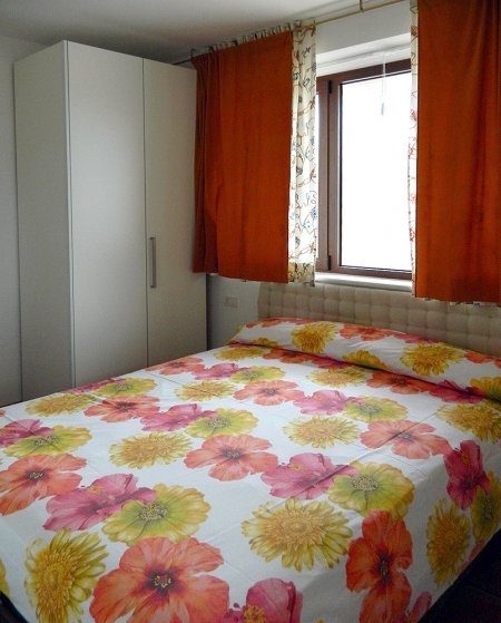 Camera con letto matrimoniale e copriletto floreale.