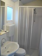 Bagno compatto con doccia, lavandino, e specchio.