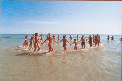 Persone in costume da bagno formano un cerchio tenendosi per mano nell'acqua.
