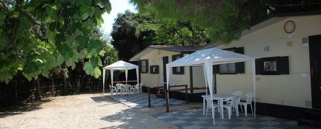 Due case prefabbricate con gazebo e tavolini all'aperto.