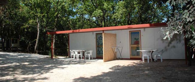 Una casa prefabbricata con sedie e tavoli esterni.