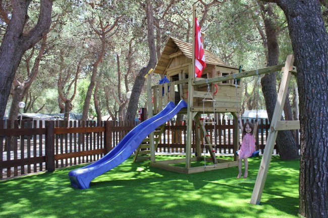 Bambina al parco giochi con scivolo blu.